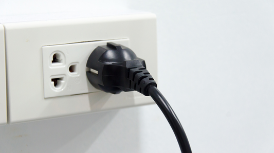 Black electrical plug connected to a white wall outlet