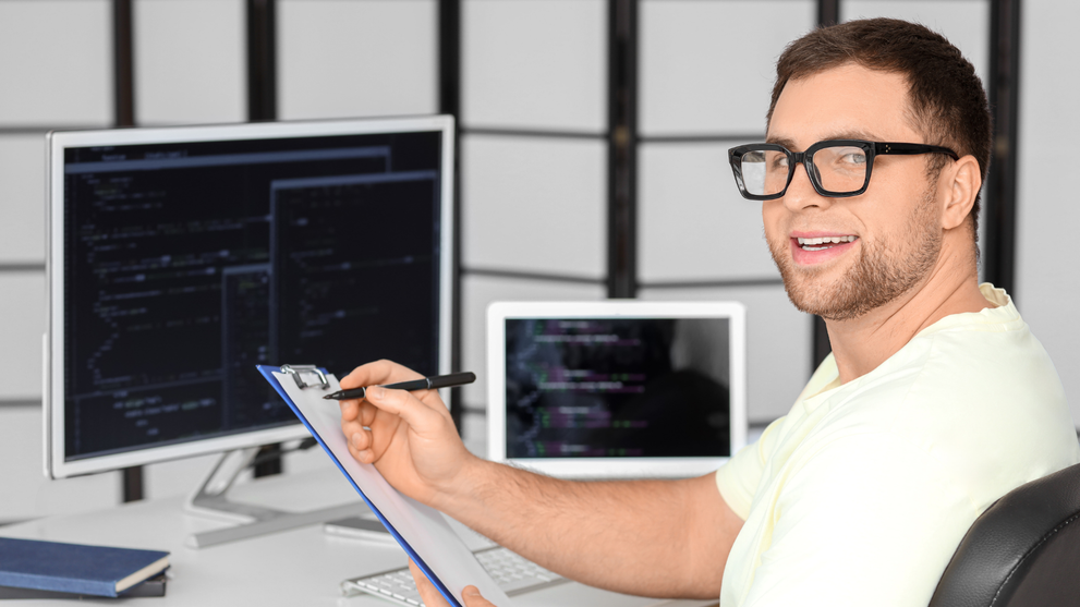 Engineering student reviewing code on computer screens