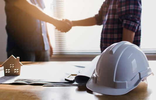 Engineers shaking hands with construction hard hat