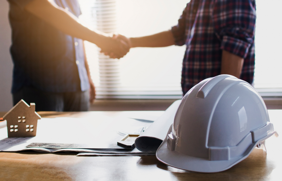 Engineers shaking hands with construction hard hat