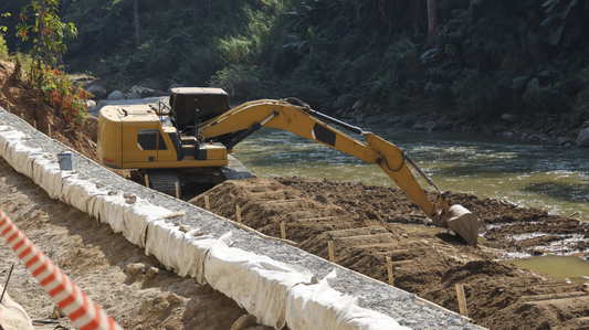 Excavator performing soil erosion control along riverbank