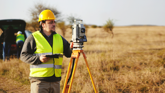 Surveyor using total station equipment in field